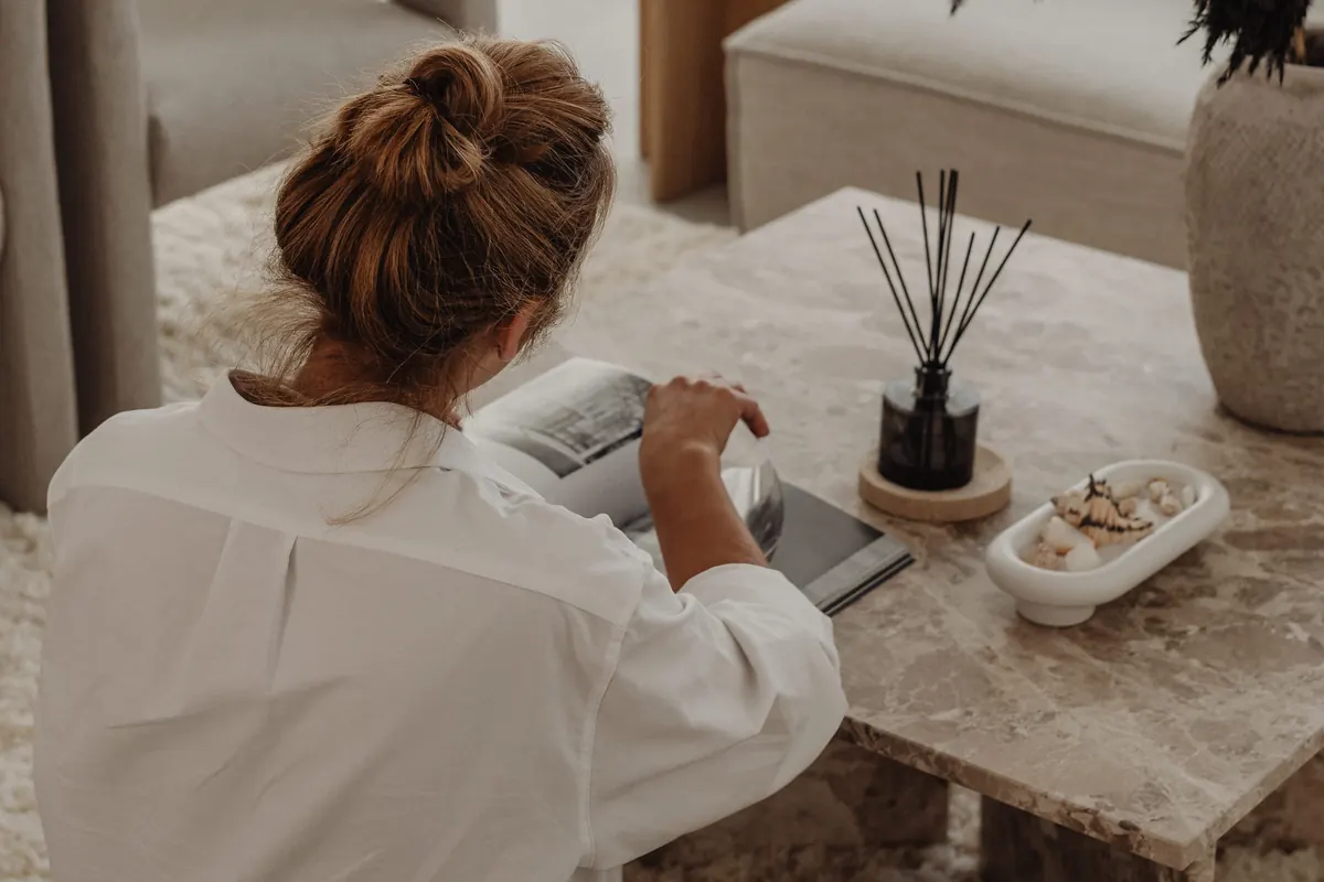 Woman seated at a marble coffee table in a calm, softly lit living room