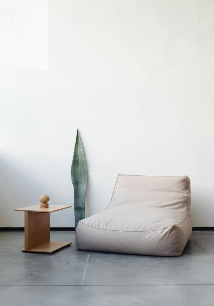 Minimal, comfortable seating area with a soft lounge chair and wooden side table